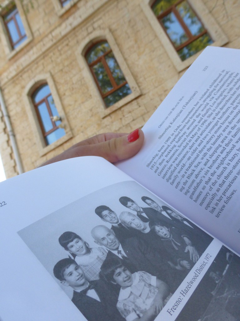 Holding book with photo of Babi Hovakim and Mami Chnkuhi with grandchildren (Fresno, 1972), while standing in front of school-turned orphanage in Ordu, where Mami Chnkuhi lived as a little girl during/after Genocide.